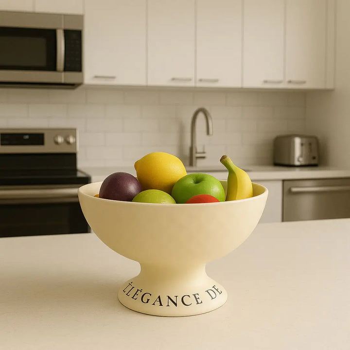 Fruteira Elegance Life Casavelle na cor creme com frutas frescas, sobre bancada de cozinha moderna e elegante.