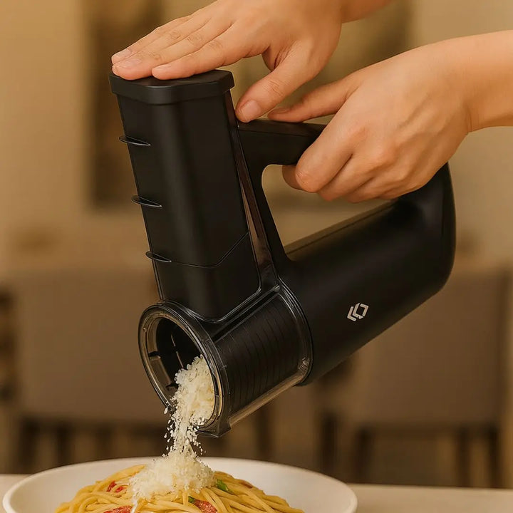 Pessoa usando o ralador de queijo elétrico Casavelle para ralar queijo fresco sobre um prato de massa em cozinha sofisticada.