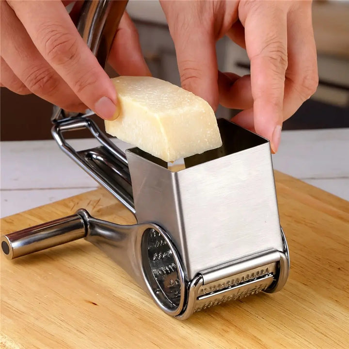 Ralador de queijo giratório inox Casavelle sendo utilizado para ralar queijo sobre tábua de madeira em cozinha moderna.